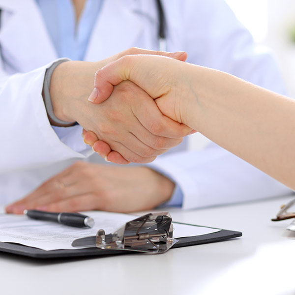 Ärztin schüttelt Hände mit Patienten